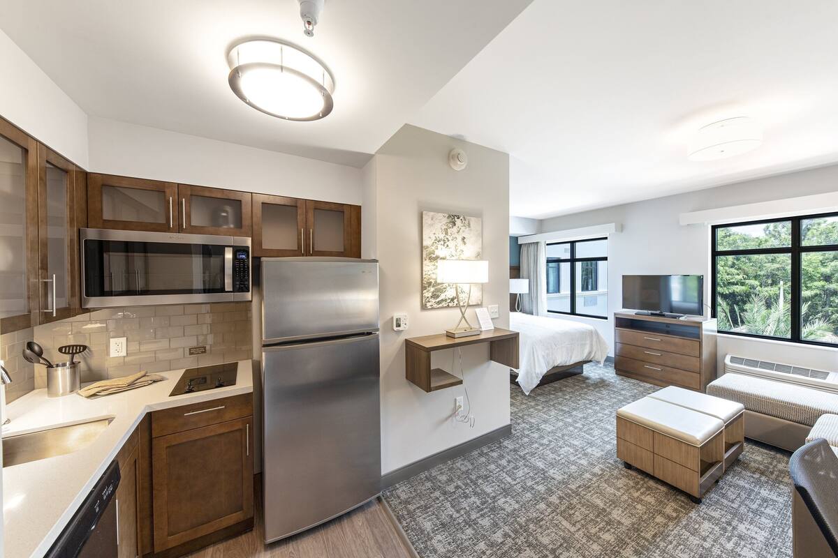 A modern kitchen with stainless steel appliances, wooden cabinets, and a built-in microwave.