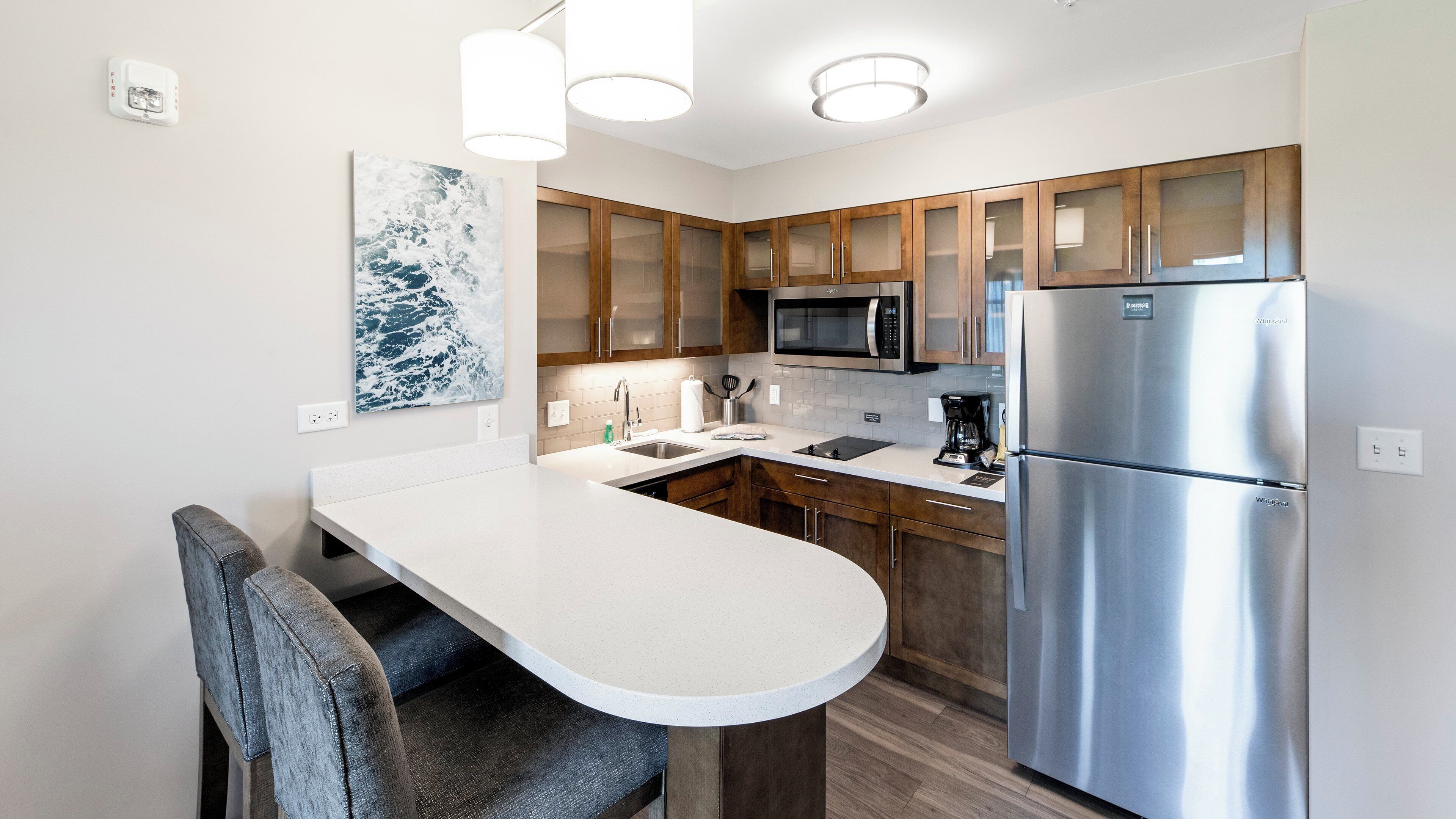 A modern kitchen with a stainless steel refrigerator, a microwave, and a white countertop.