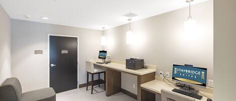 A hotel room with a desk, computer, and seating area.