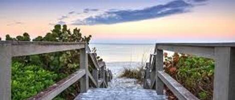 A wooden staircase leading to a beach with a clear view of the ocean.