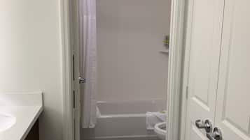Un bagno con una vasca da bagno bianca, un water e un lavandino.