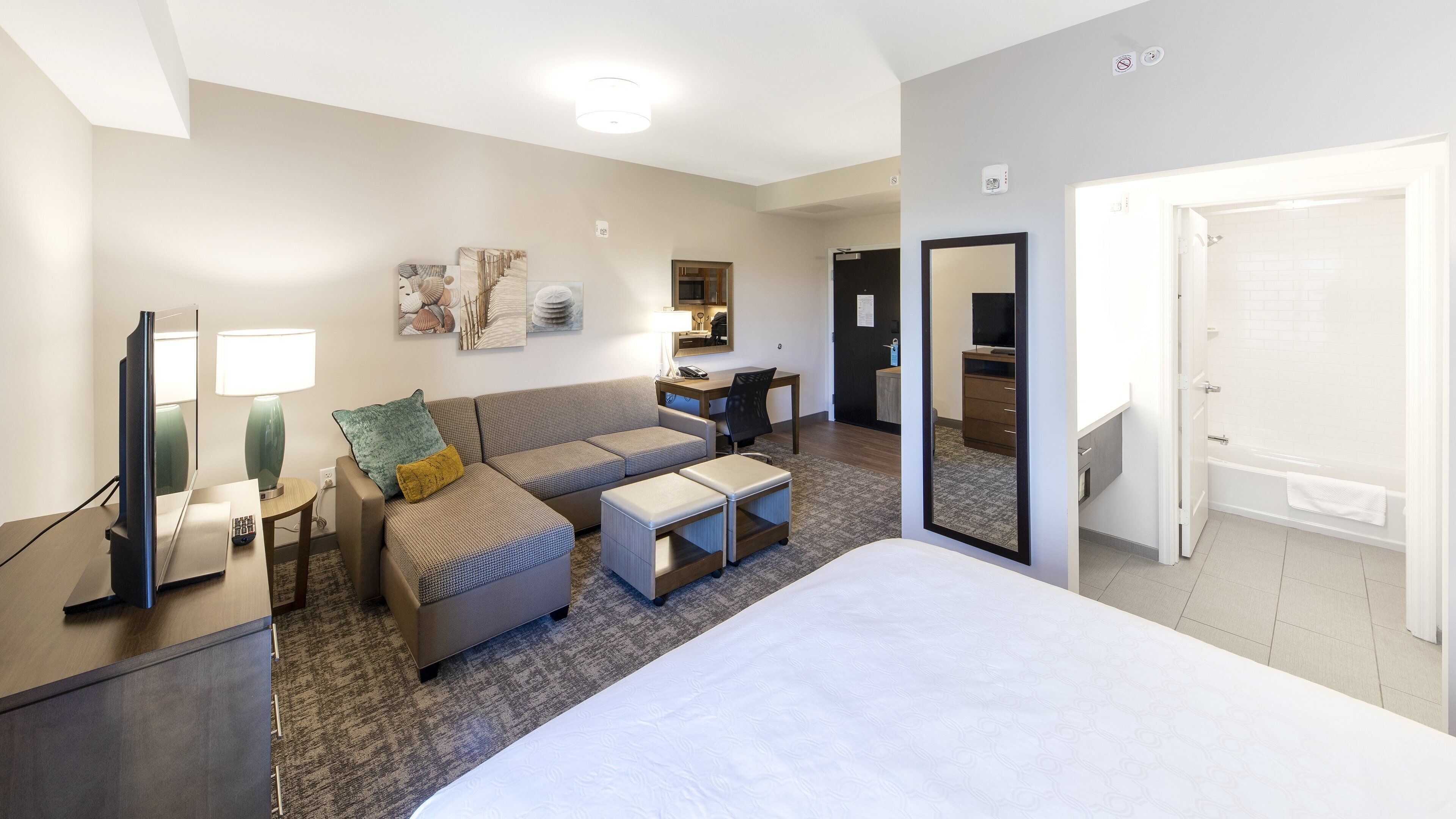 Habitación de hotel con cama, sofá, escritorio, televisor y baño.