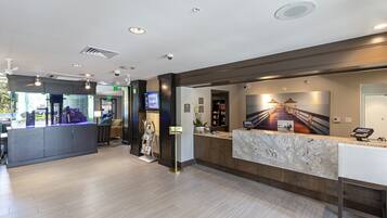 Una moderna zona de recepción de hotel con mostrador de mármol, pantalla digital y mostrador de recepción.