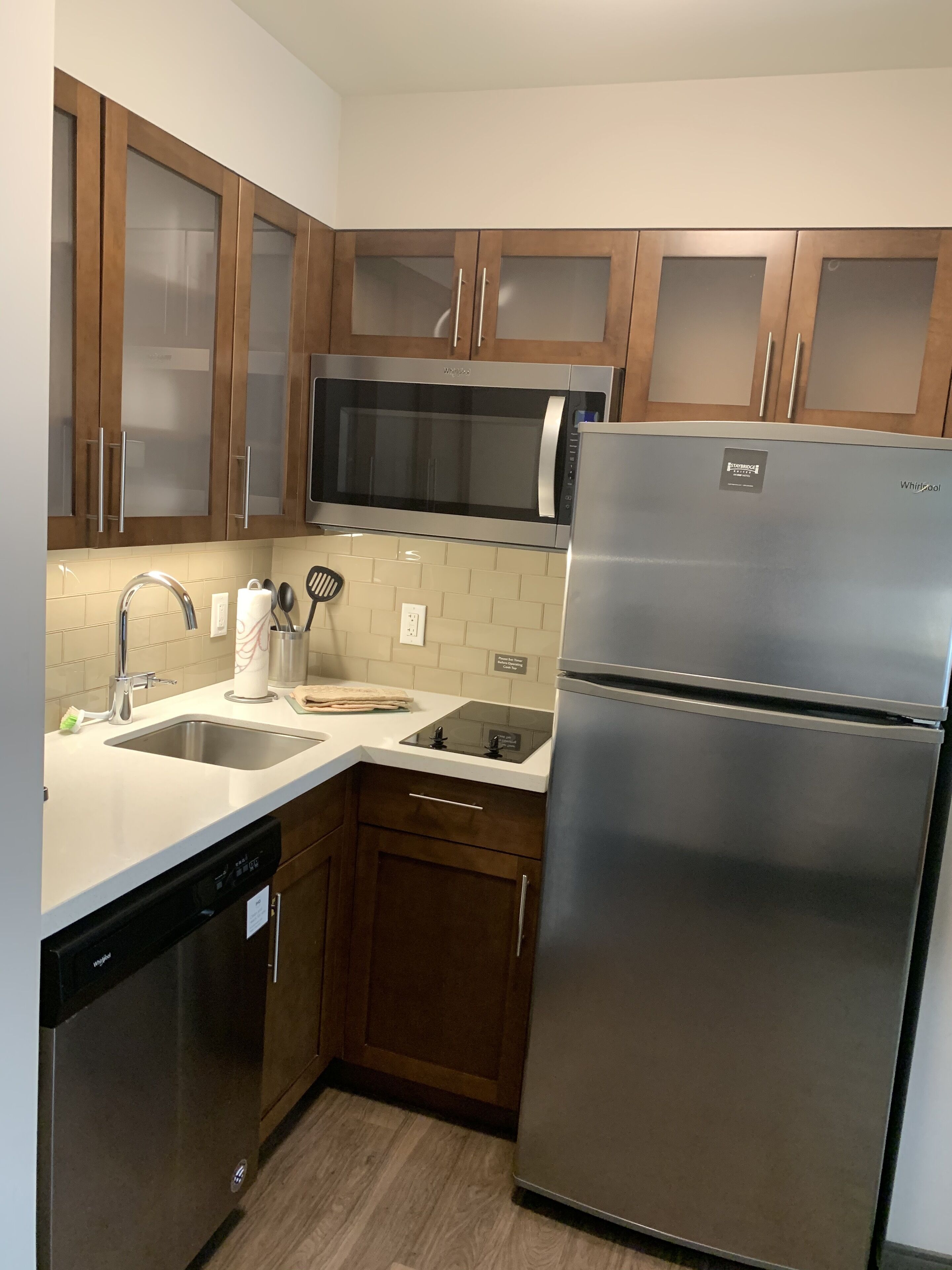 A modern kitchen with stainless steel appliances, wooden cabinets, and a dishwasher.