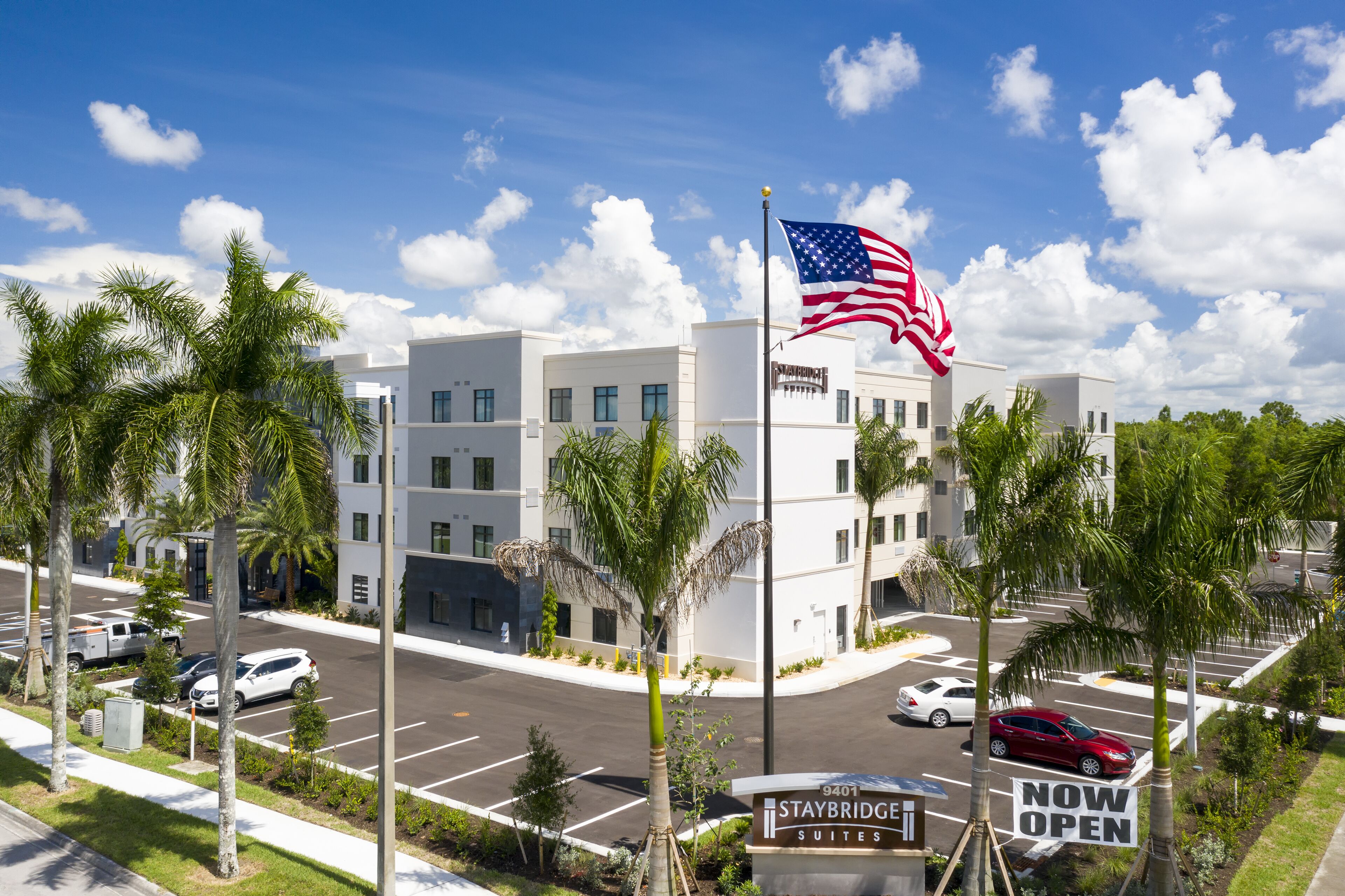 A modern hotel with a sign indicating 'Staybridge Suites' and 'Now Open'.