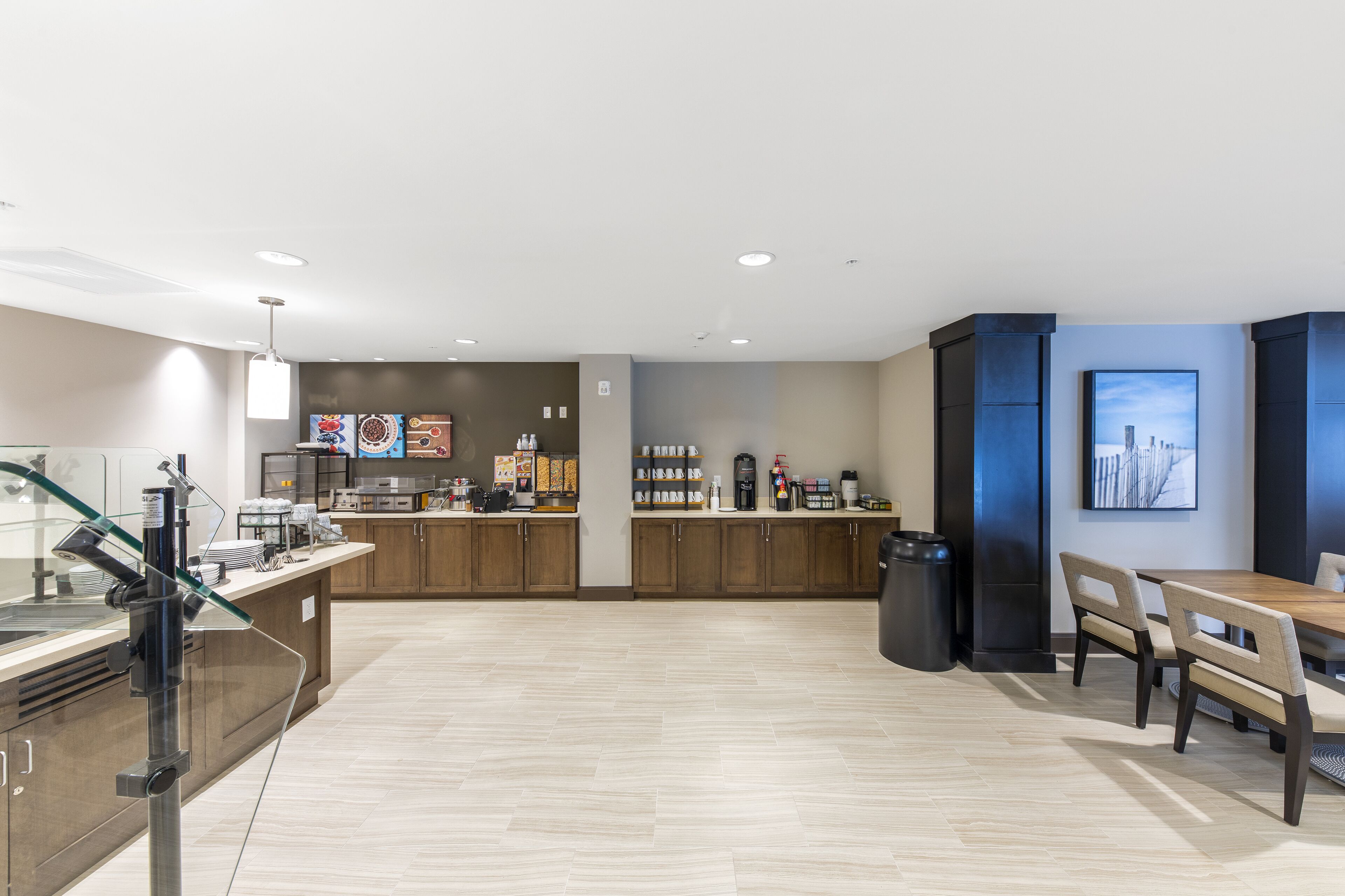 A modern hotel lobby with a coffee bar, seating area, and artwork on the walls.