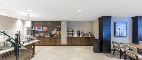 A modern hotel lobby with a coffee bar, seating area, and artwork on the walls.