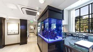 A hotel lobby with a large aquarium, seating area, and a framed artwork on the wall. - Staybridge Suites Naples – Marco Island by IHG (Naples)