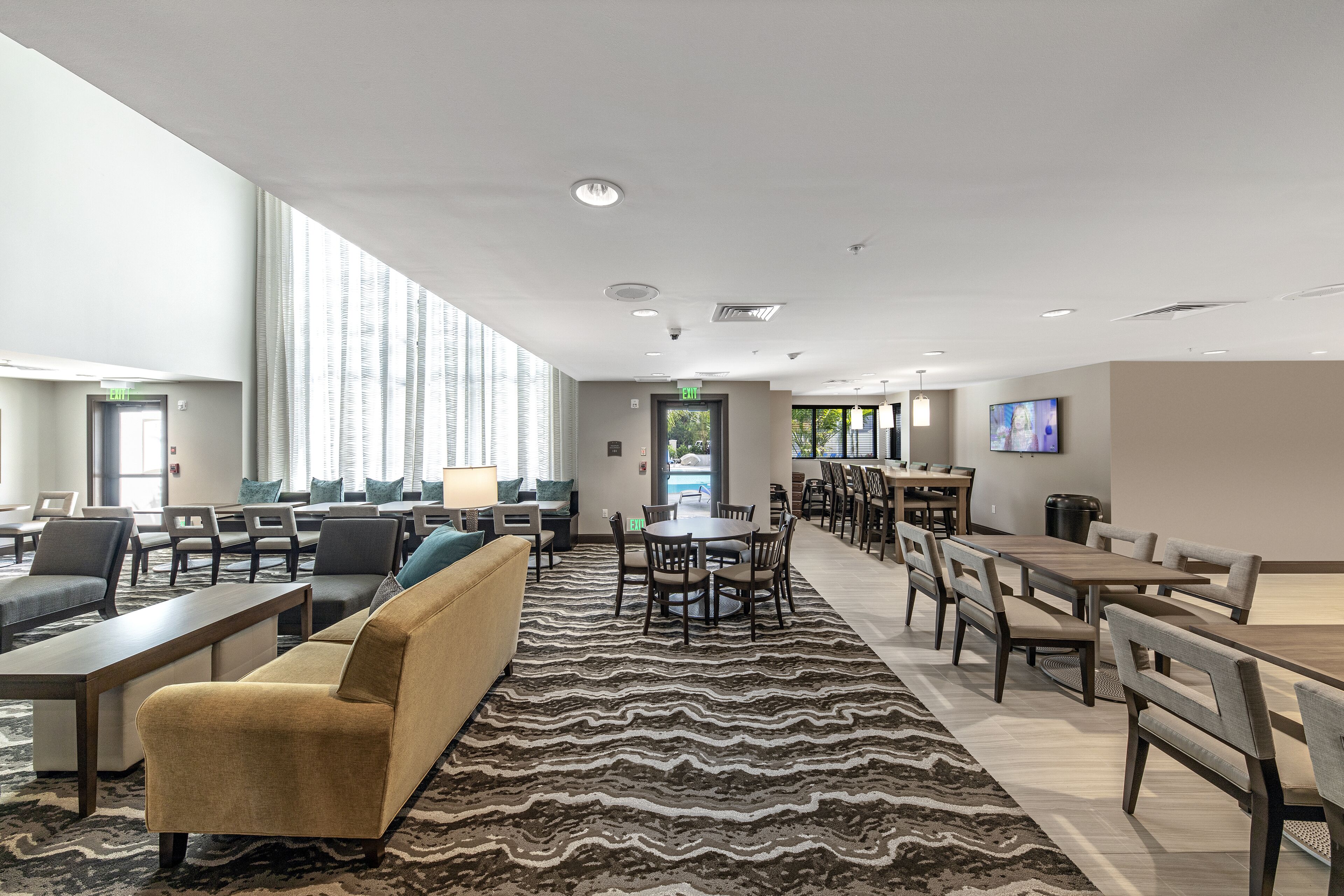 A spacious hotel lobby with a large seating area, a pool view, and a modern design.