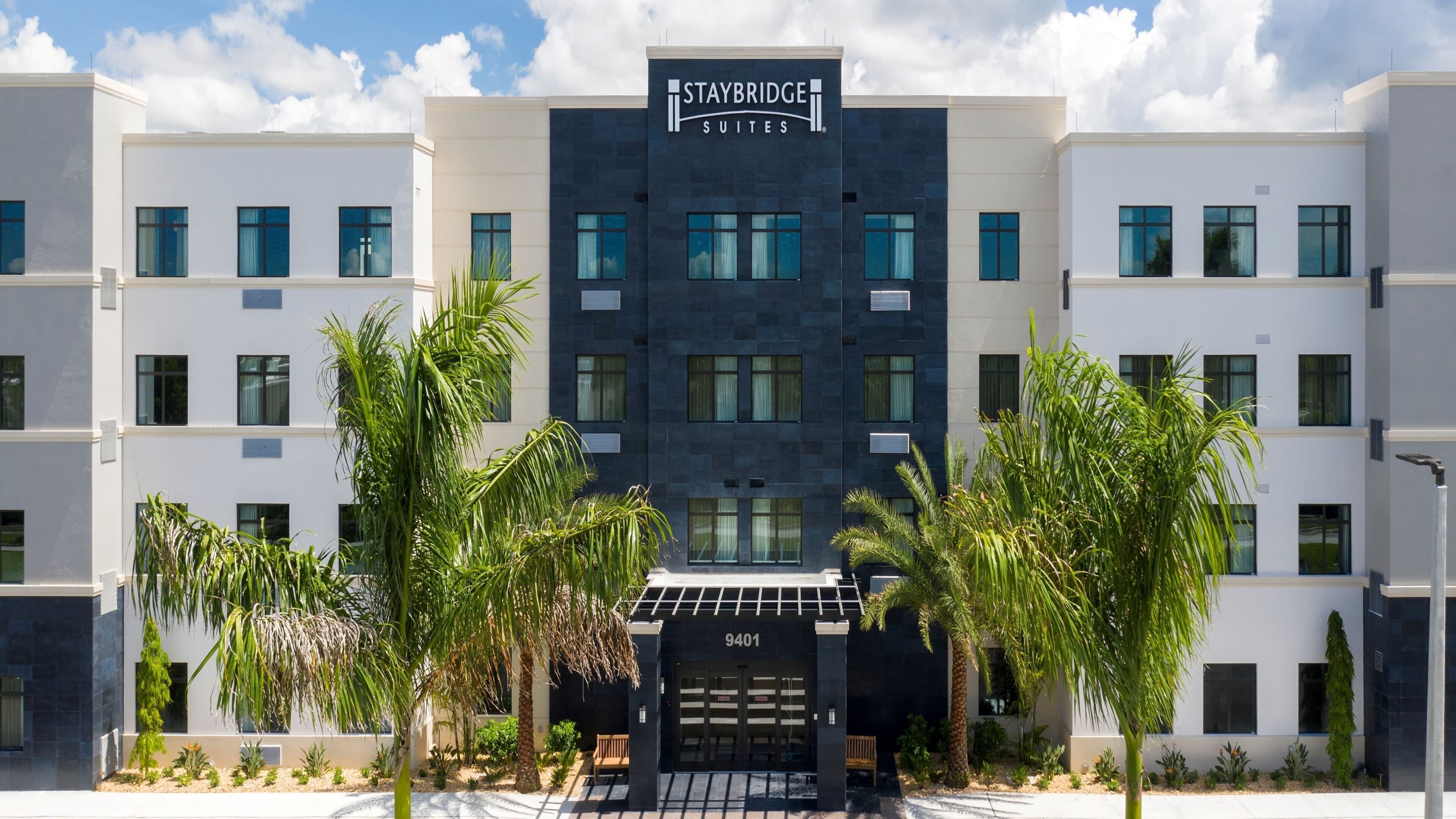 Edificio del hotel Staybridge Suites con fachada moderna, ventanas amplias y una entrada central.
