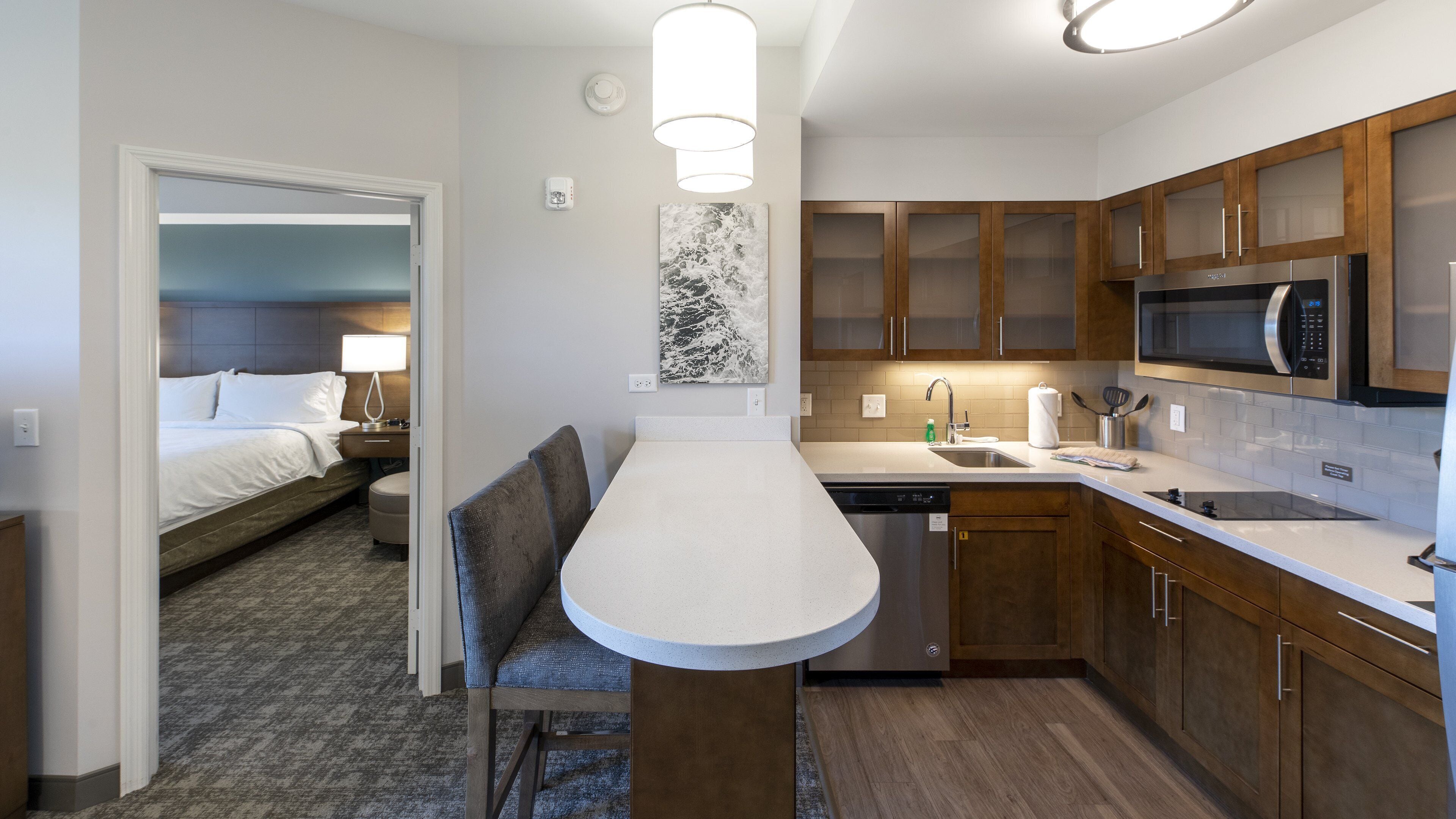 A compact hotel room with a kitchenette, a dining area, and a bed.