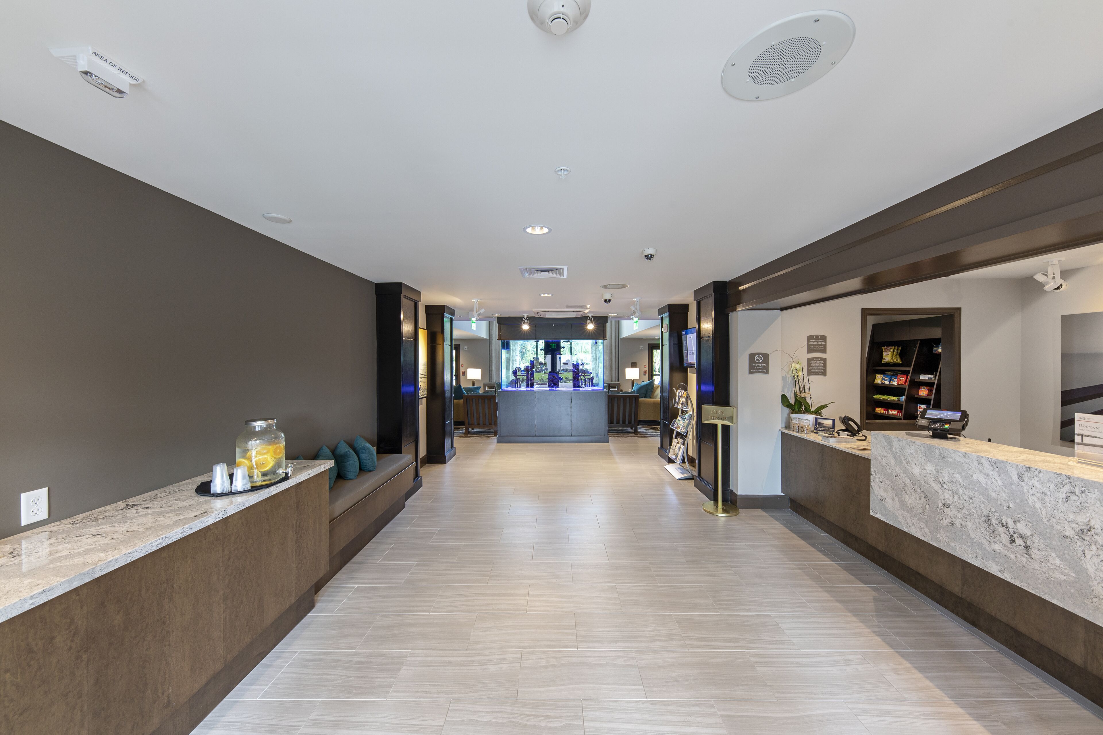 A hotel reception area with a marble counter, a seating area with cushions, and a view into the lobby.