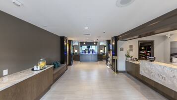 A hotel reception area with a marble counter, a seating area with cushions, and a view into the lobby.