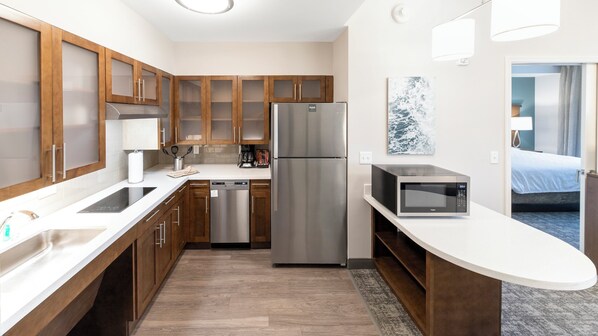 A modern kitchen with wooden cabinets, stainless steel appliances, and a microwave.