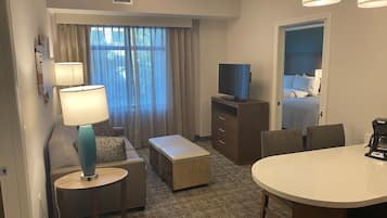 A hotel room with a bed, a TV, a desk, a chair, a lamp, and a coffee maker.