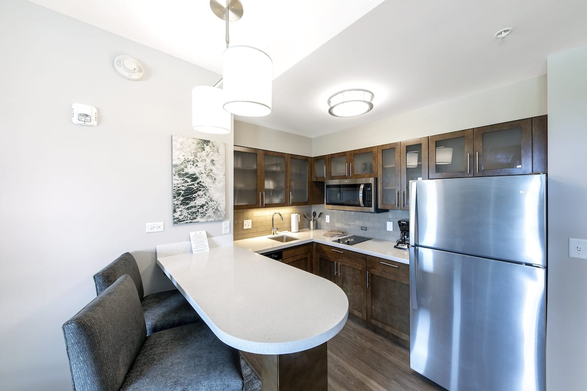 A modern kitchen with a central island, stainless steel appliances, and wooden cabinets.