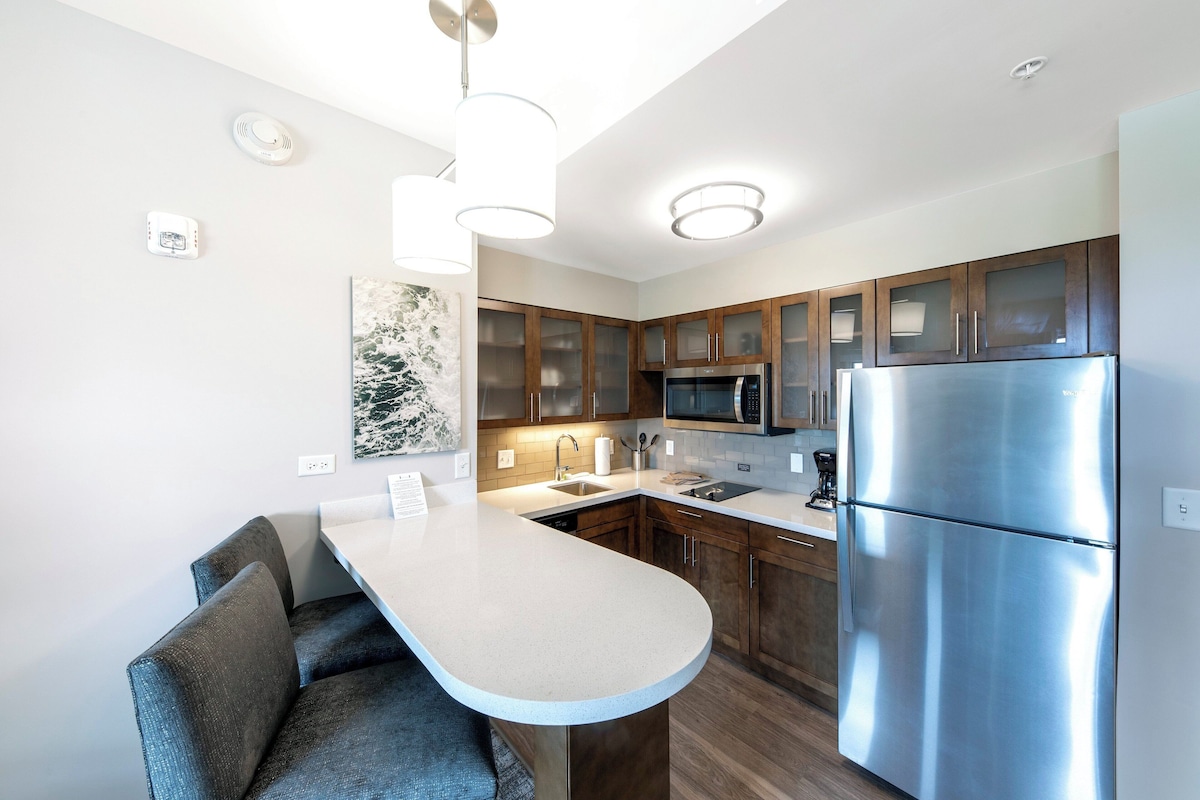 A modern kitchen with a central island, stainless steel appliances, and wooden cabinets.