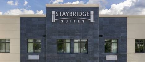 Ein Staybridge Suites Gebäude mit moderner Fassade, großen Fenstern und blauem Himmel.