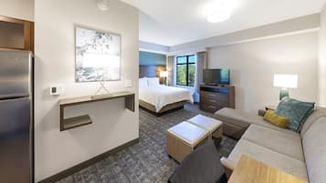 A hotel room with a bed, a sofa, a TV, a refrigerator, a desk, and a window with a view.