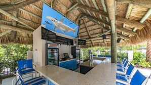 A restaurant with a thatched roof, blue chairs, and a counter with a menu. - Staybridge Suites Naples – Marco Island by IHG (Naples)