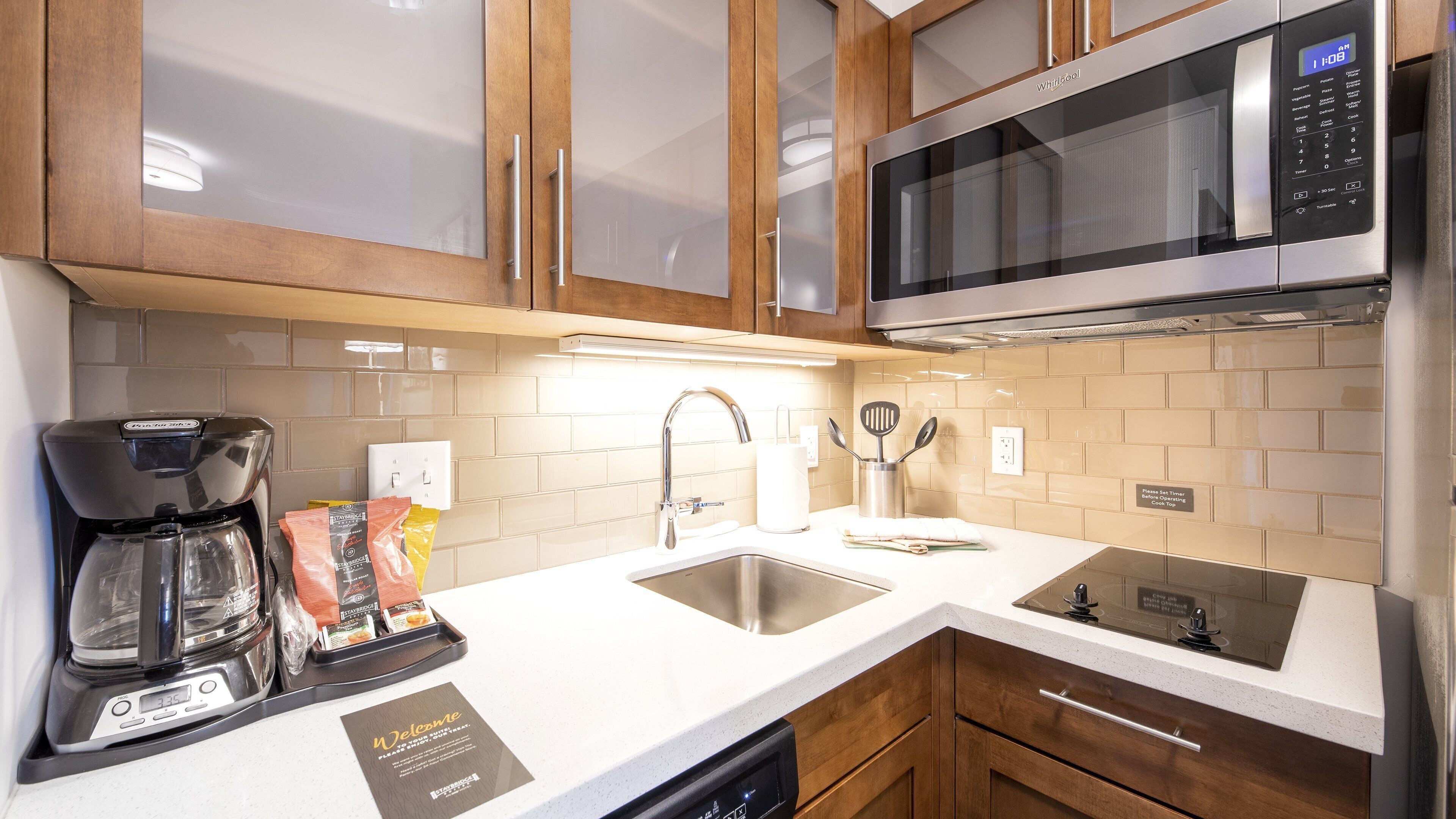 A modern kitchen with a coffee maker, a microwave, and a sink.