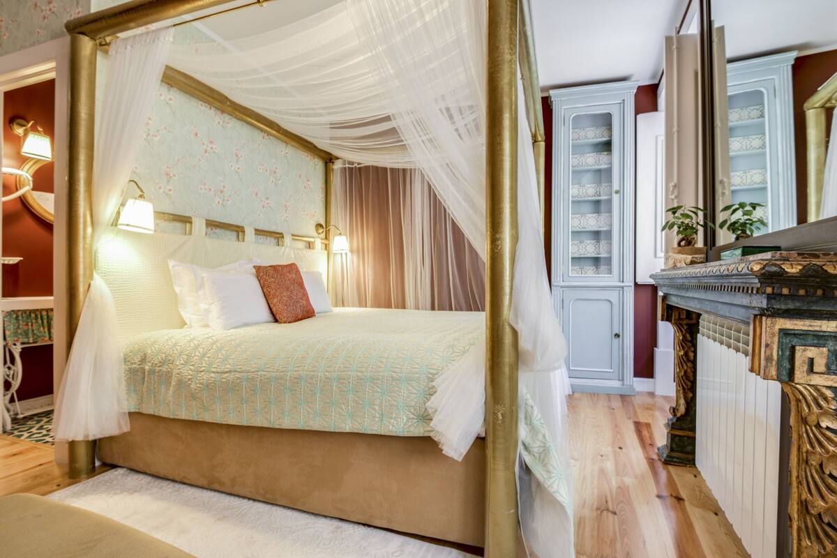 Un lit à baldaquin avec des lampes de chevet et une tête de lit ornée de motifs floraux.