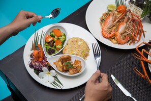 A dining table with plates of food, utensils, and a napkin. - Nai Ya Hotel (Chiang Rai)
