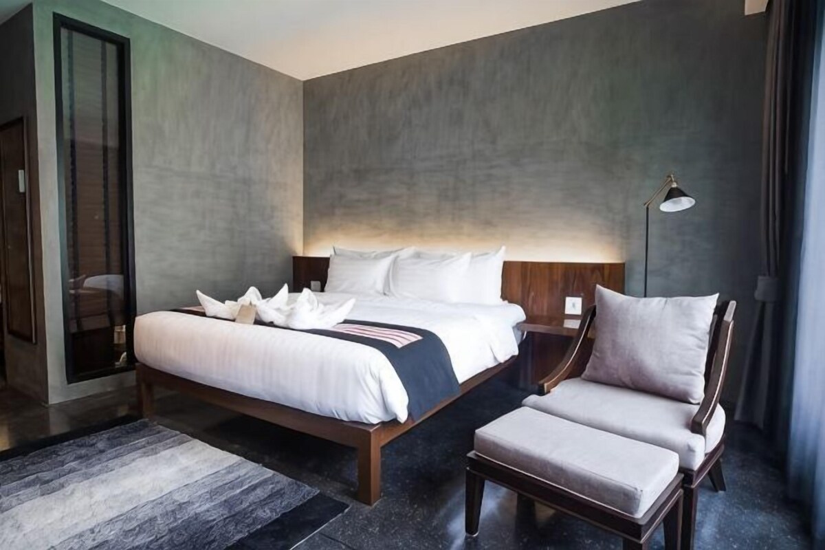 Ein modernes Schlafzimmer mit einem großen Bett, einem Nachttisch, einem Sessel und einer Stehlampe.