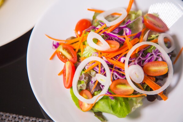 A plate of mixed salad with lettuce, tomatoes, carrots, and onions. - Nai Ya Hotel (Chiang Rai)