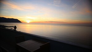 Ein Sonnenuntergangsblick von einem Balkon mit Holztisch und Stühlen.