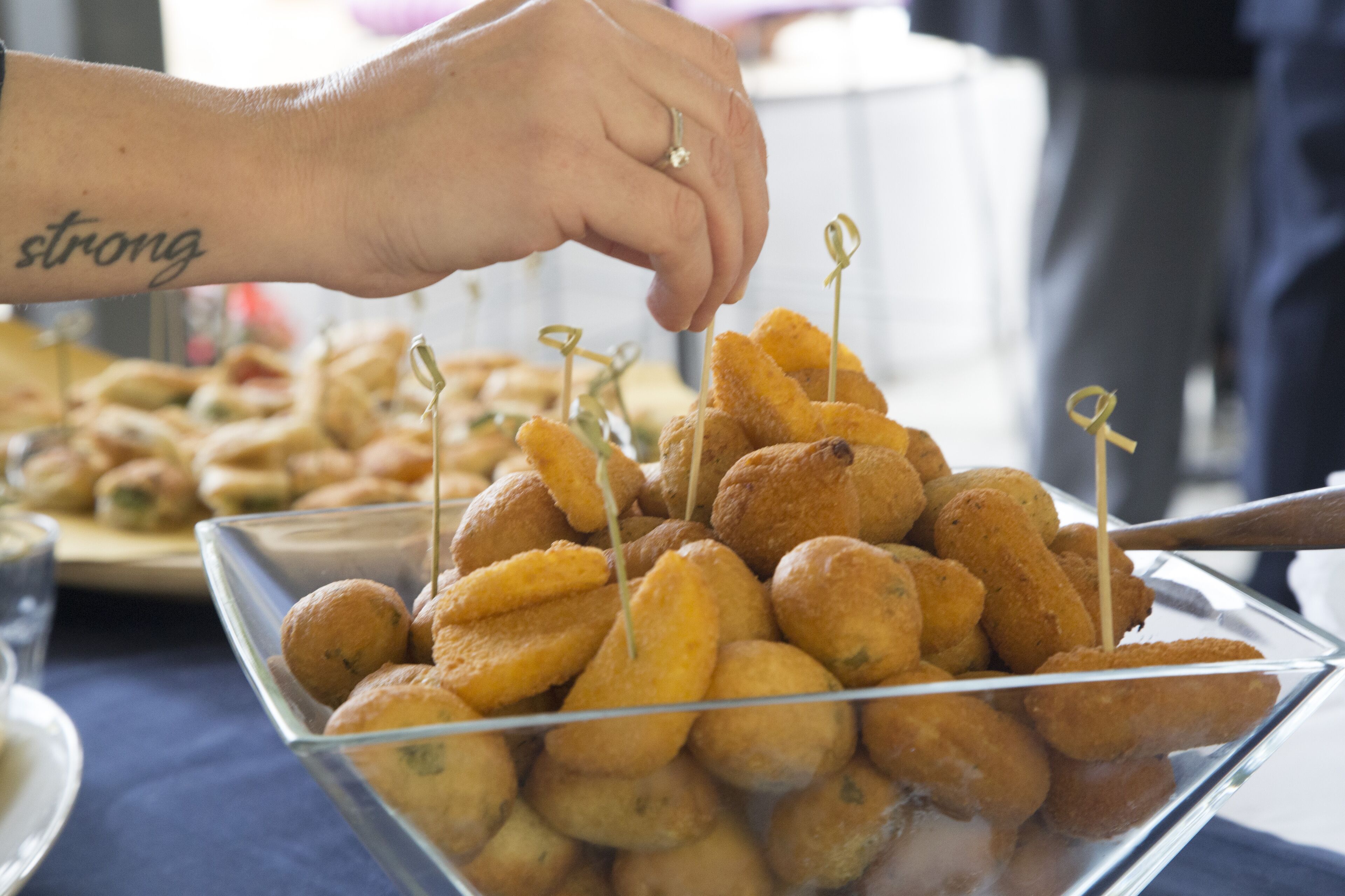 Una mano colocando un palillo en un cuenco de bocadillos empanizados.