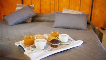 Una cama impecable con una bandeja de desayuno que incluye jugo de naranja, café y muffins.