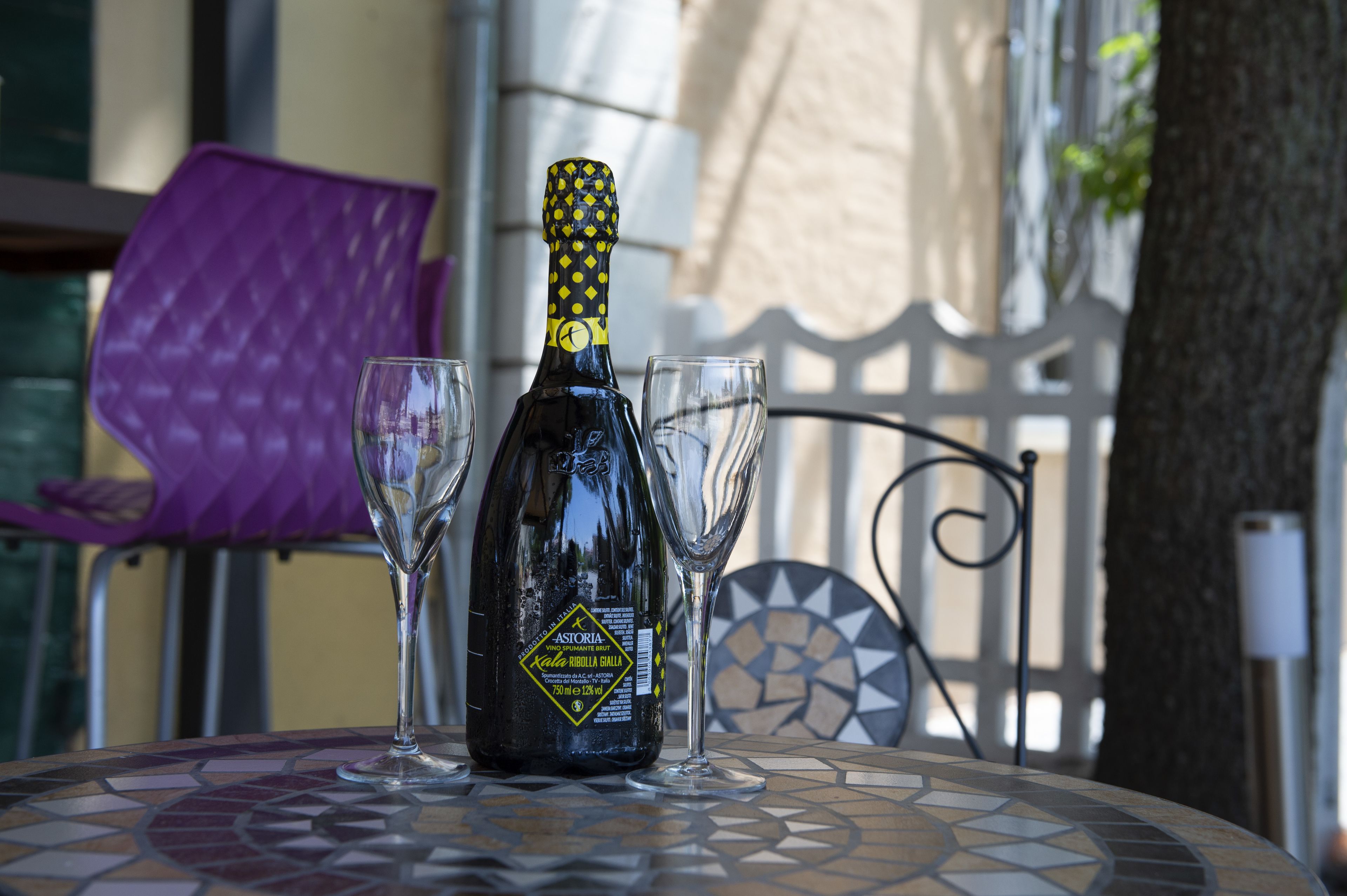 A bottle of Astoria wine on a table with two glasses.