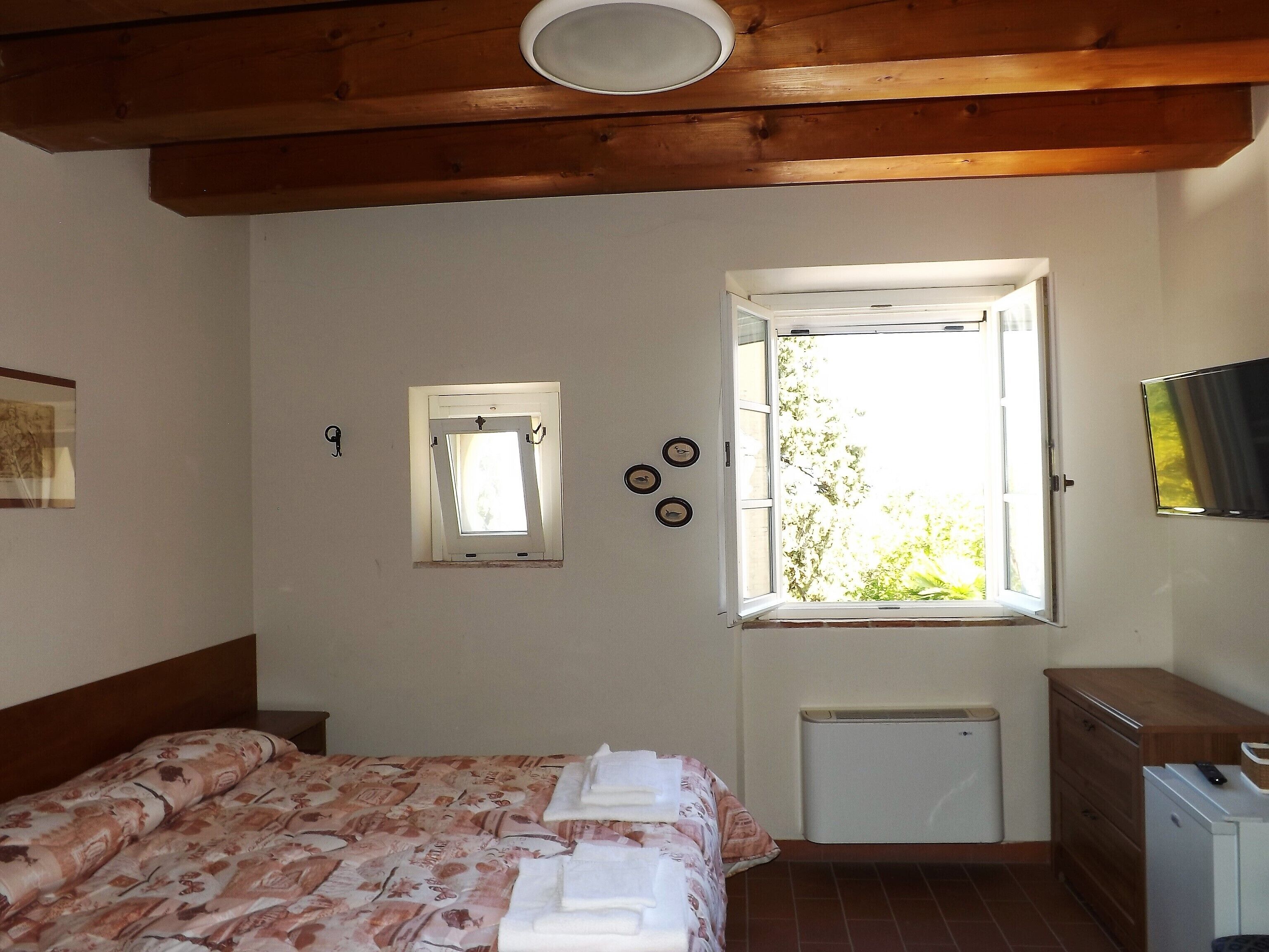 Un dormitorio con cama, ventana, radiador y cómoda.