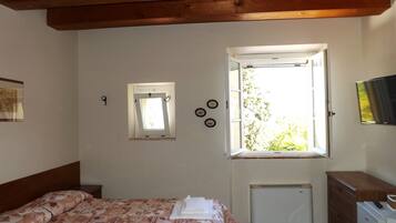 Un dormitorio con cama, ventana, radiador y cómoda.