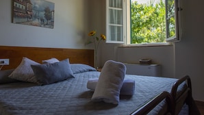 A bedroom with a bed, pillows, a nightstand, a vase with flowers, and a painting on the wall. - Tenuta Villa Colle Sereno (Montemarciano)