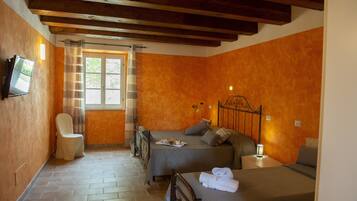 Una habitación con dos camas, una silla, un televisor y una ventana con cortinas.