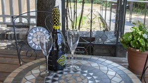 A round table with a mosaic tile design, a bottle of champagne, and two glasses on it. - Tenuta Villa Colle Sereno (Montemarciano)