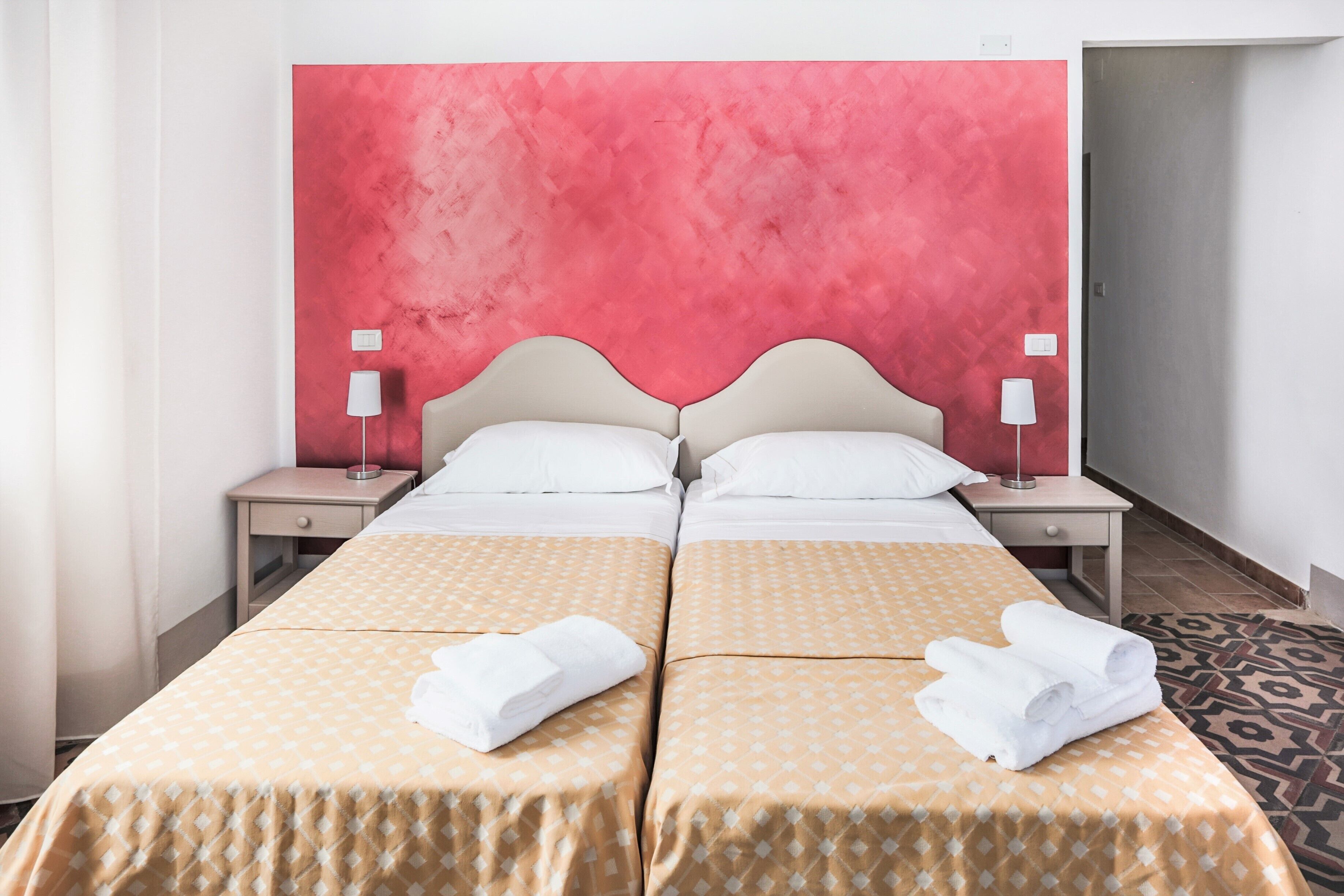 Ein Doppelbett mit zwei Kissen, ein Nachttisch mit Lampe und ein gemustertes Teppich.