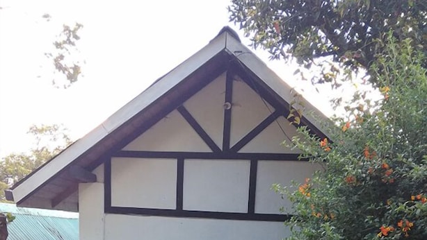 A building with a gabled roof, multiple windows, and a stone wall in front. - Sincere Wilderness (Nuwara Eliya)