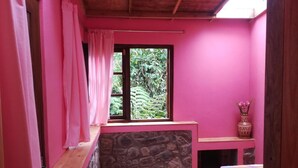 A pink room with a stone fireplace, a window with curtains, and a wooden ceiling. - Sincere Wilderness (Nuwara Eliya)