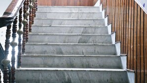 A marble staircase with wooden balusters and a wooden handrail. - Hotel Holydon (Siliguri)