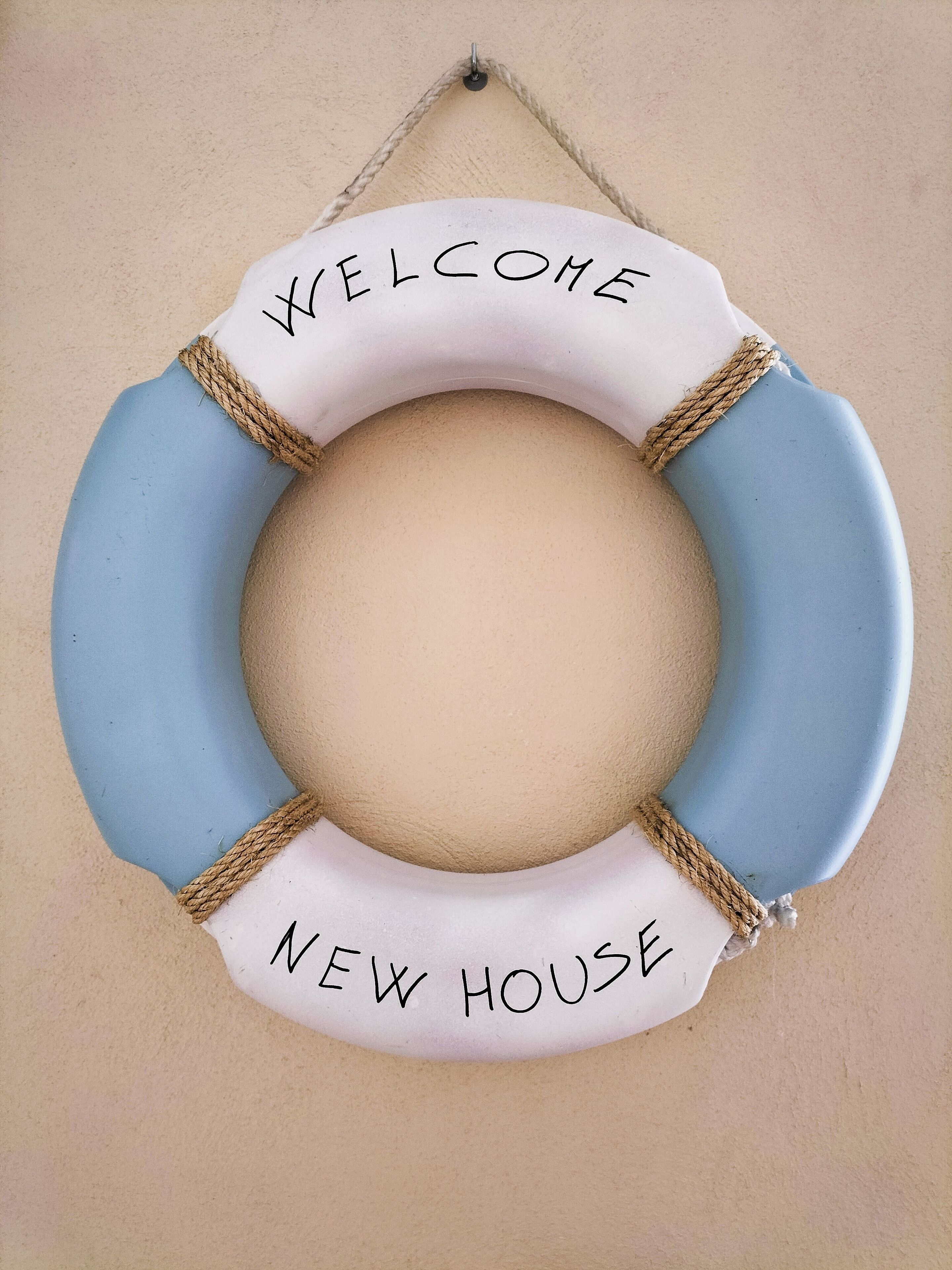 Ein rundes Schild mit der Aufschrift 'WELCOME NEW HOUSE'.