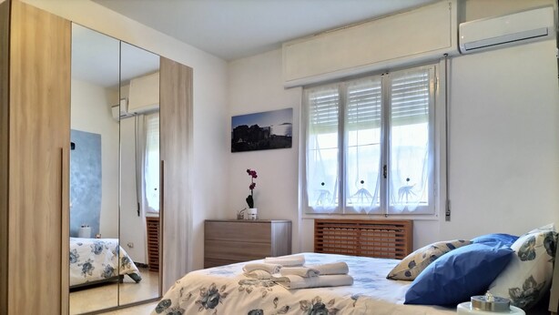 A bedroom with a bed, a dresser, a mirror, and a window with curtains.