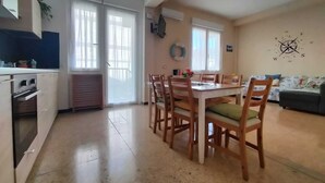 A spacious living area with a dining table, chairs, a sofa, and a kitchen area with cabinets and a stove.