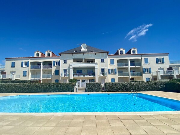A large building with a swimming pool in front.