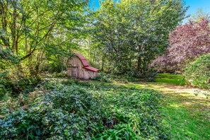 Surrounded by lush greenery and flowering trees, this serene garden features a charming rustic structure.