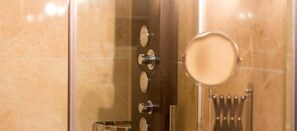 A bathroom with a glass shower enclosure, a mirror, and a set of toiletries.