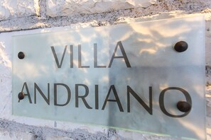 A sign with the text "VILLA ANDRIANO" mounted on a wall.