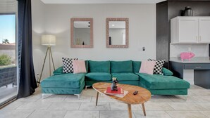 A modern living room with a green sectional sofa, two mirrors, a coffee table, and a kitchen area with white cabinets. - Near Las Vegas Strip and Airport: Games & Arcades- Southpoint less than 5 mins. (Las Vegas)